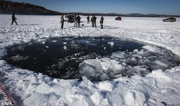 Russian policemen stands near an eight-meter hole where the meteorite fell 